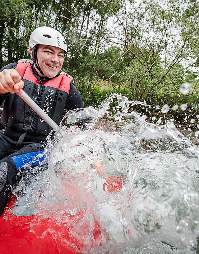 Group of young people rafting on wild water with helmets and life vests during a summer holiday in Flachau with almlust
