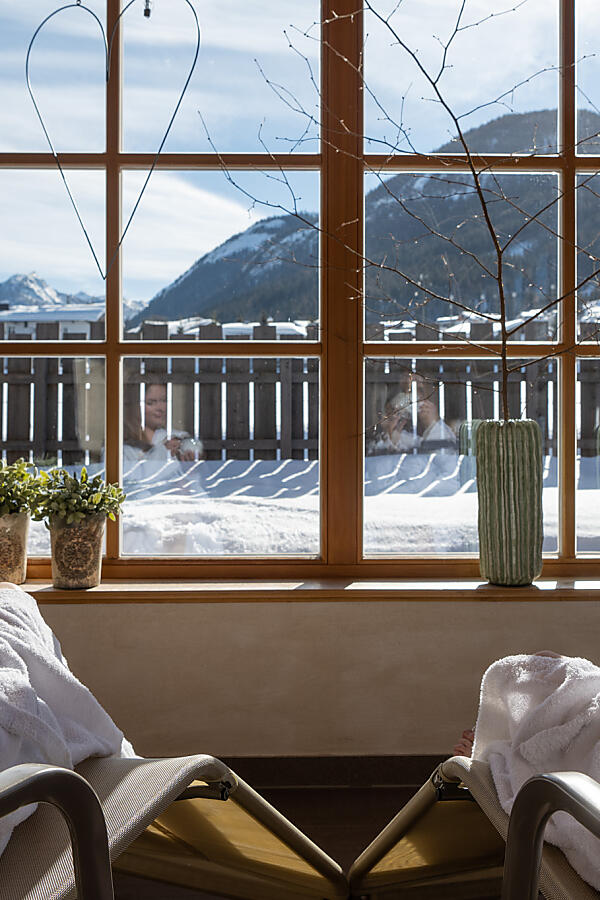  Women in bathrobes enjoying tea in the almlust winter lounge with mountain view