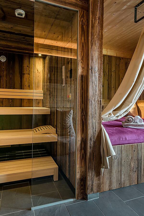 Private spa suite with sauna and mountain view Spa suite with wooden sauna, cozy lounger and panoramic windows at Almlust