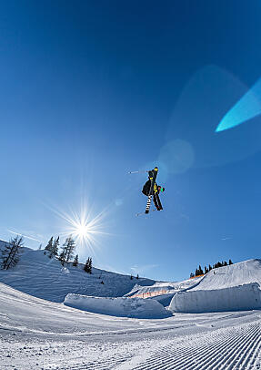 Freestyle jump in Absolut Park Flachau Freestyle skier in the snowpark in Flachau under a clear blue sky