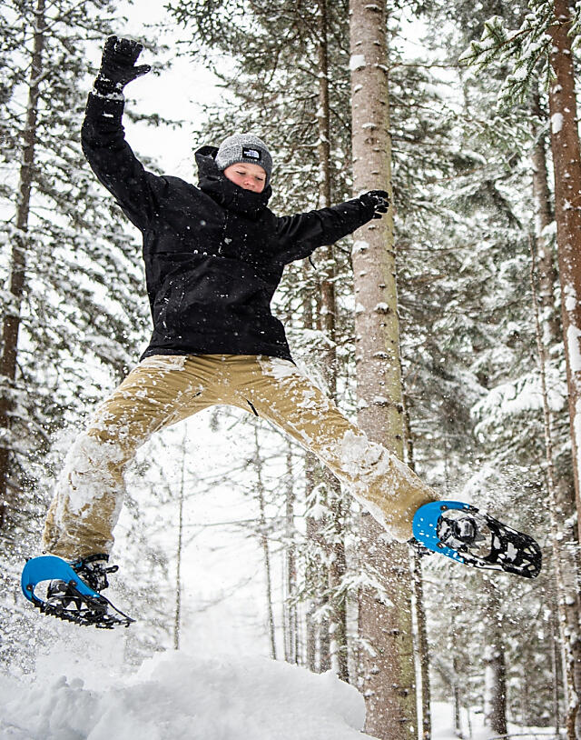 Young person snowshoeing through the snowy winter forest in Flachau