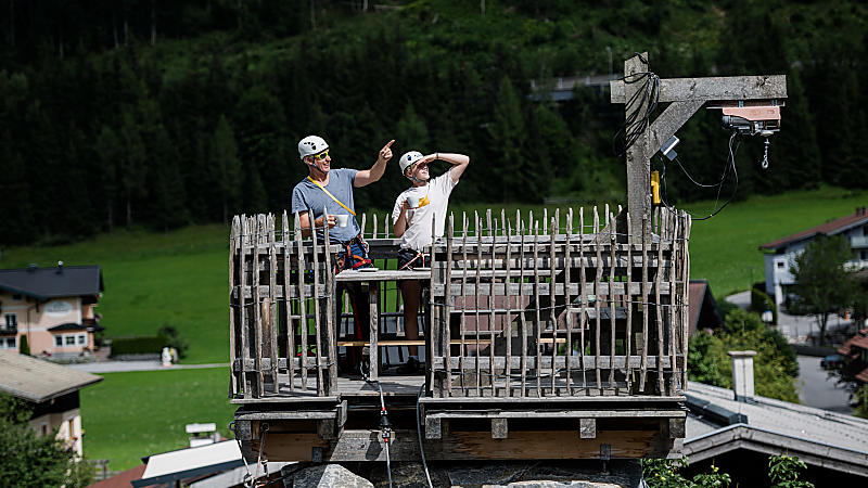 Two people with helmets on the Almrock climbing tower platform planning the climb