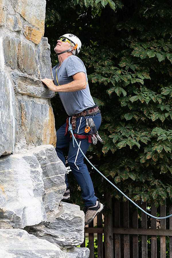 Adult climbing the almlustrock in Flachau, belayed by a teenager on the ground