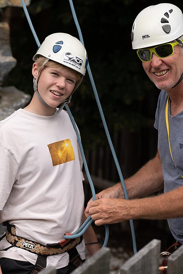 Instructor checking harness and rope for a young climber at Almrock climbing tower in Flachau