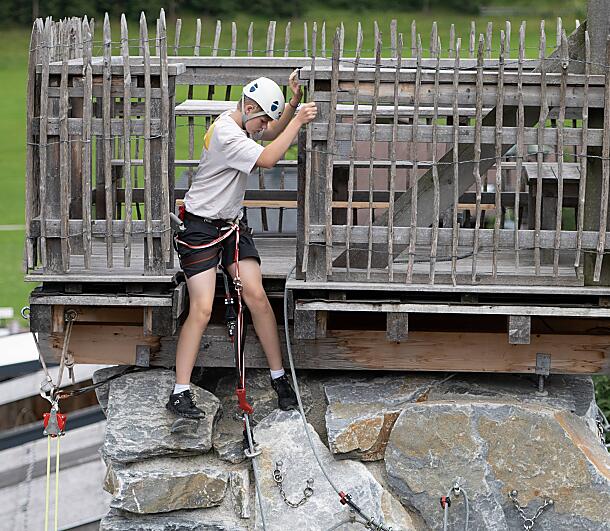 Junge Person beginnt den Kletteraufstieg vom Holzturm am almlustrock in Flachau