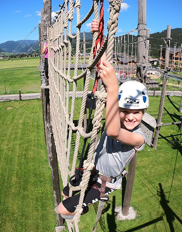 Kind klettert im Hochseilgarten Flachau über ein großes Seilnetz