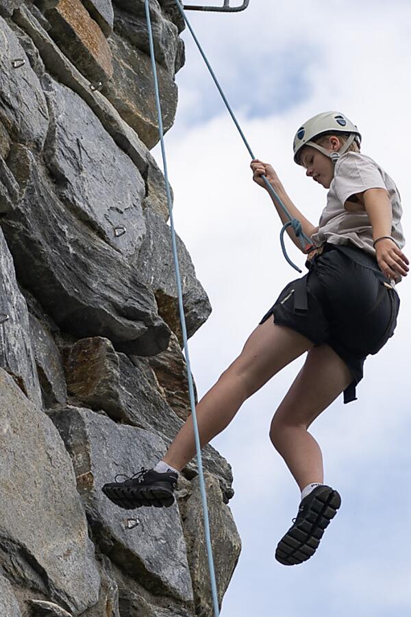 Abseiling adventure in Flachau – pure adrenaline from the almlust roof Girl abseiling down the climbing wall at almlust Flachau wearing helmet and harness