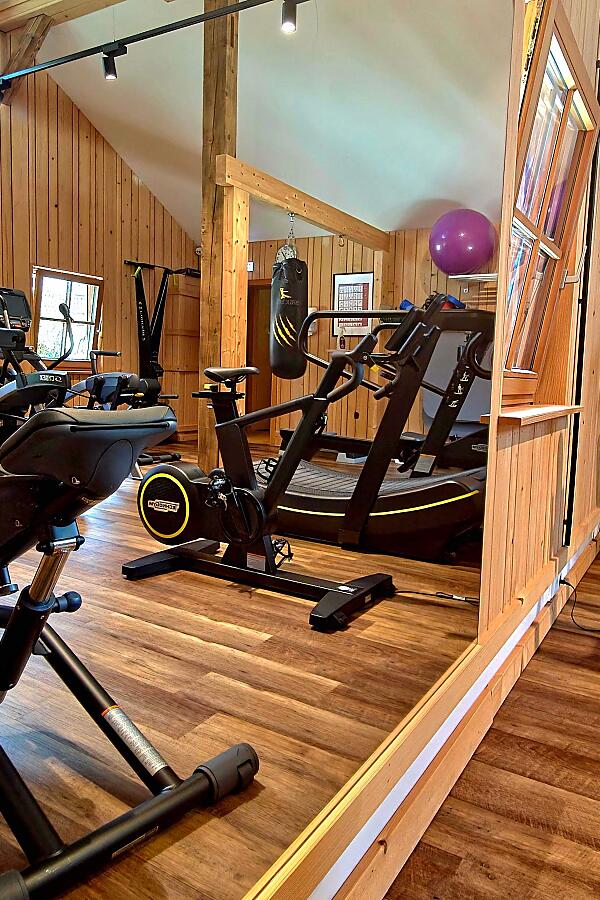 Dein Workout-Spot mitten in den Bergen Fitnessraum mit modernen Geräten und Holzverkleidung im almlust Fit Stadl