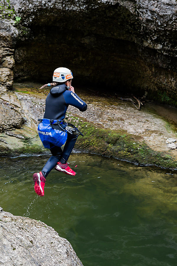 Person in canyoning wetsuit jumping into a natural rock pool in Flachau, Austria