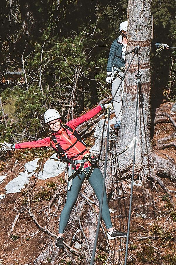 Frau mit Klettergurt auf dem Seilparcours beim Klettersteig in Flachau