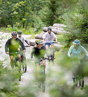 Group of e-bikers riding through forest roads in Flachau – active summer in Austria