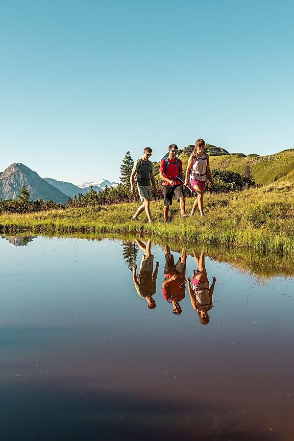 Wandern in Flachau – Bergsee mit Spiegelung und Panorama Wanderer am klaren Bergsee mit Spiegelung in der Naturkulisse von Flachau