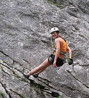 Woman ropes down a rock.