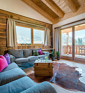 Heller Wohnbereich in der almlust mit großer Couch, Holzbalken, Balkon und Blick auf die Berge