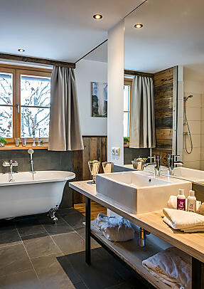 Bright bathroom at almlust with freestanding bathtub, double washbasin and large mirror