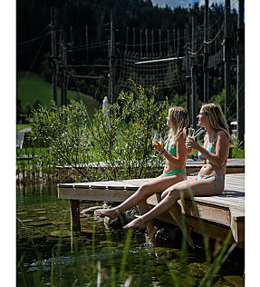 Two guests relaxing at the Almsee on a wooden pier at almlust in Flachau