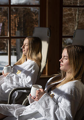 Zwei Gäste entspannen im Bademantel im Alm Spa der almlust in Flachau mit Tee
