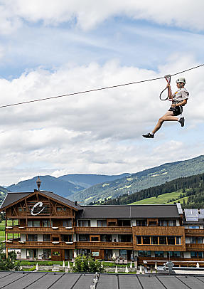 Person fährt mit dem Flying Fox über die almlust in Flachau vor Bergkulisse