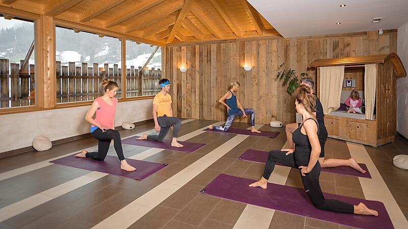 Mehrere Personen praktizieren Yoga in einem hellen Raum der almlust mit Matten und Holzatmosphäre