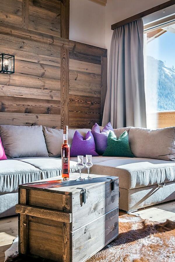 Heller Wohnbereich in der almlust mit Sofa, Holzwänden, Balkon und Blick auf die Berge