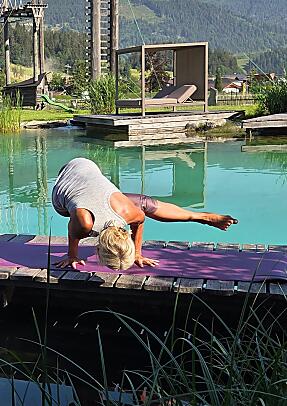 Participant practicing outdoor yoga by the natural swimming pond during the Cool Down Days retreat at almlust Flachau, Austria.