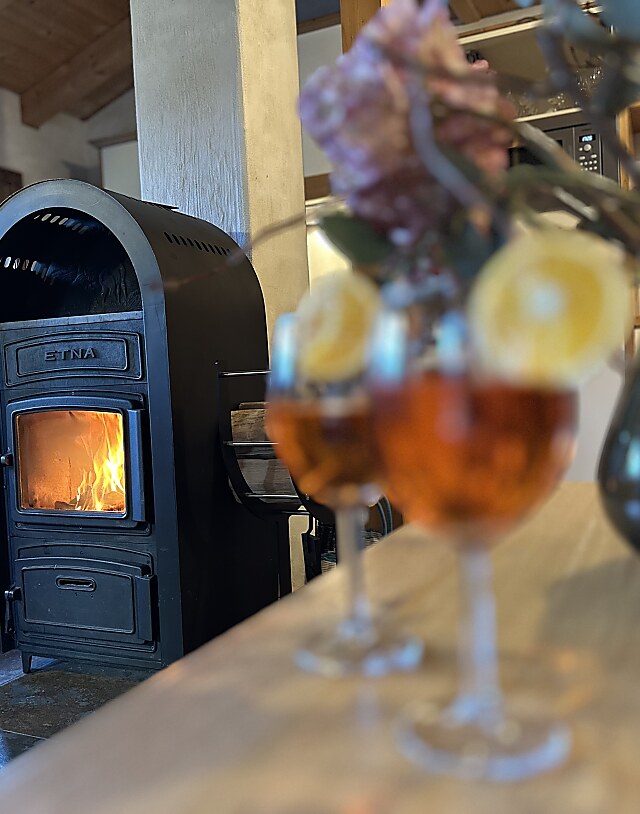 Chaletwohnraum mit Aperolgläsern und brennendem Kaminofen