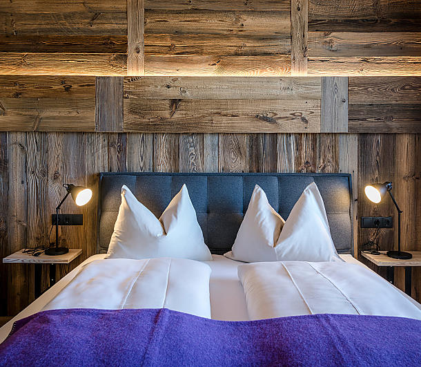 Gemütliches Doppelbett mit Holzvertäfelung und Bergblick im Hintergrund